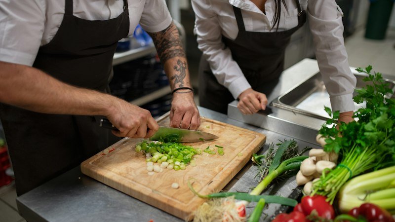 Cooks using the best chef knife under 50 to chop fresh vegetables on a wooden board